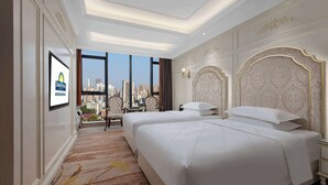 Habitación de hotel con dos camas, vistas a la ciudad, televisión y piso alfombrado.
