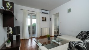 A modern living room with a glass coffee table, a sofa, a TV, and a plant. - Apartments Heidi with shared Pool (Ap 1) (Nova Vas)