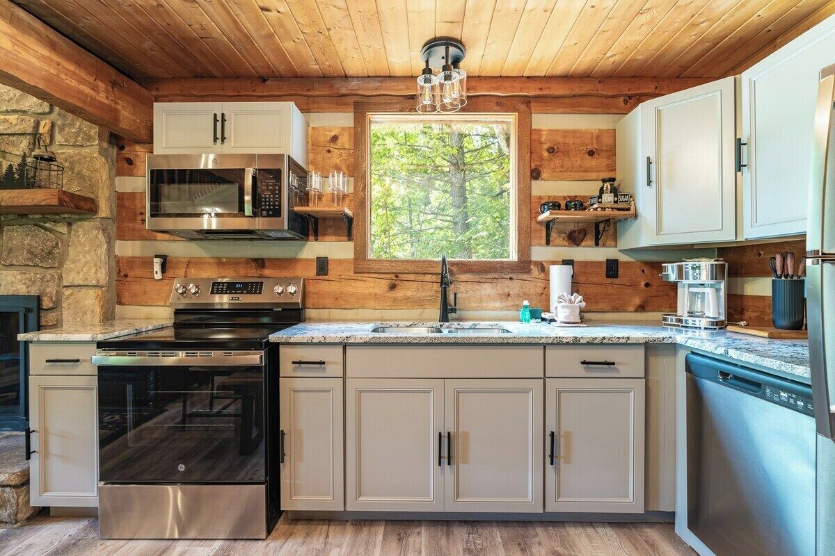 Une cuisine moderne dotée d’appareils électroménagers en acier inoxydable, de murs en bois et d’une grande fenêtre.