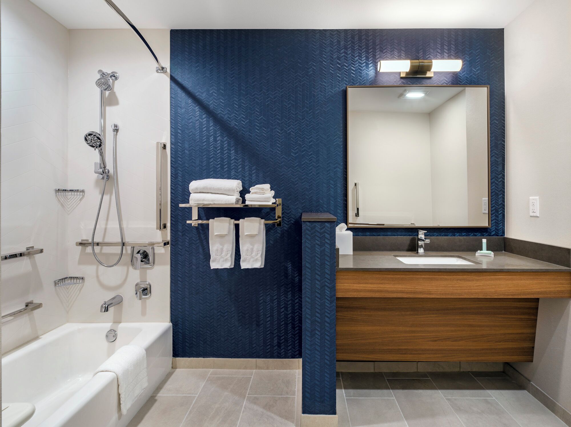 Een moderne badkamer met een bad, douche en wastafel met spiegel.