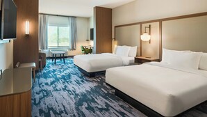A hotel room with two beds, a desk, a chair, a TV, and a large window with curtains.