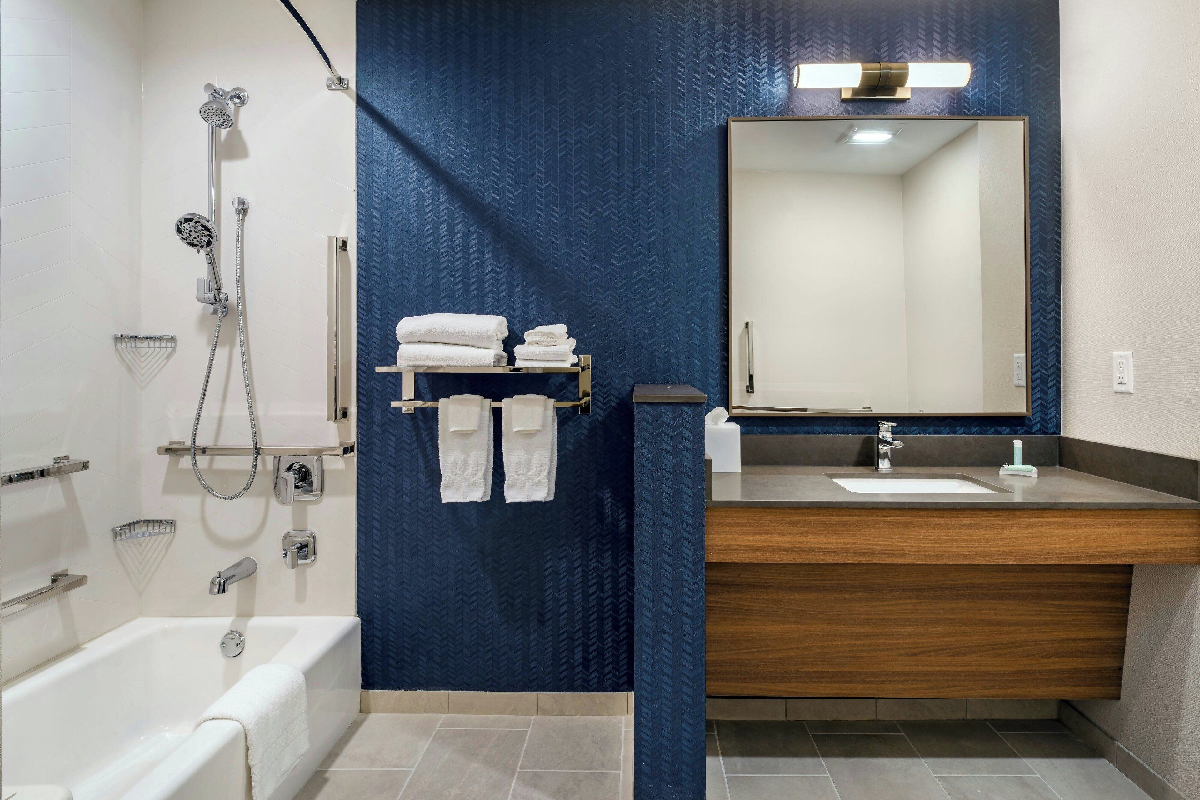 A modern bathroom with a bathtub, shower, and vanity with a mirror.