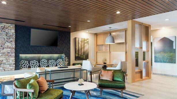 A modern living room with a stone wall, a flat-screen TV, a sofa set, a coffee table, and a bookshelf.