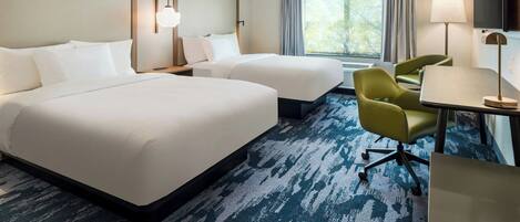 A hotel room with two beds, a desk with a chair, a TV, and a window with curtains.