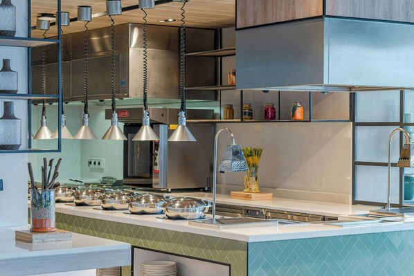 Una cocina moderna con electrodomésticos de acero inoxidable, una isla central con pileta e iluminación colgante.