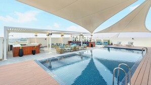 A rooftop pool area with a bar, seating, and a view of the city.