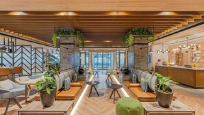 A modern lobby with seating areas, a reception desk, and a staircase.