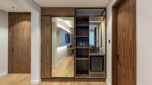 A modern interior with a wooden wardrobe, a built-in microwave, and a small refrigerator.