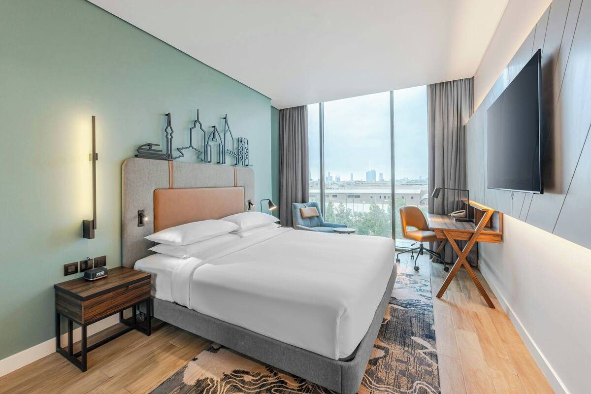 A modern hotel room with a large bed, a desk, and a TV.