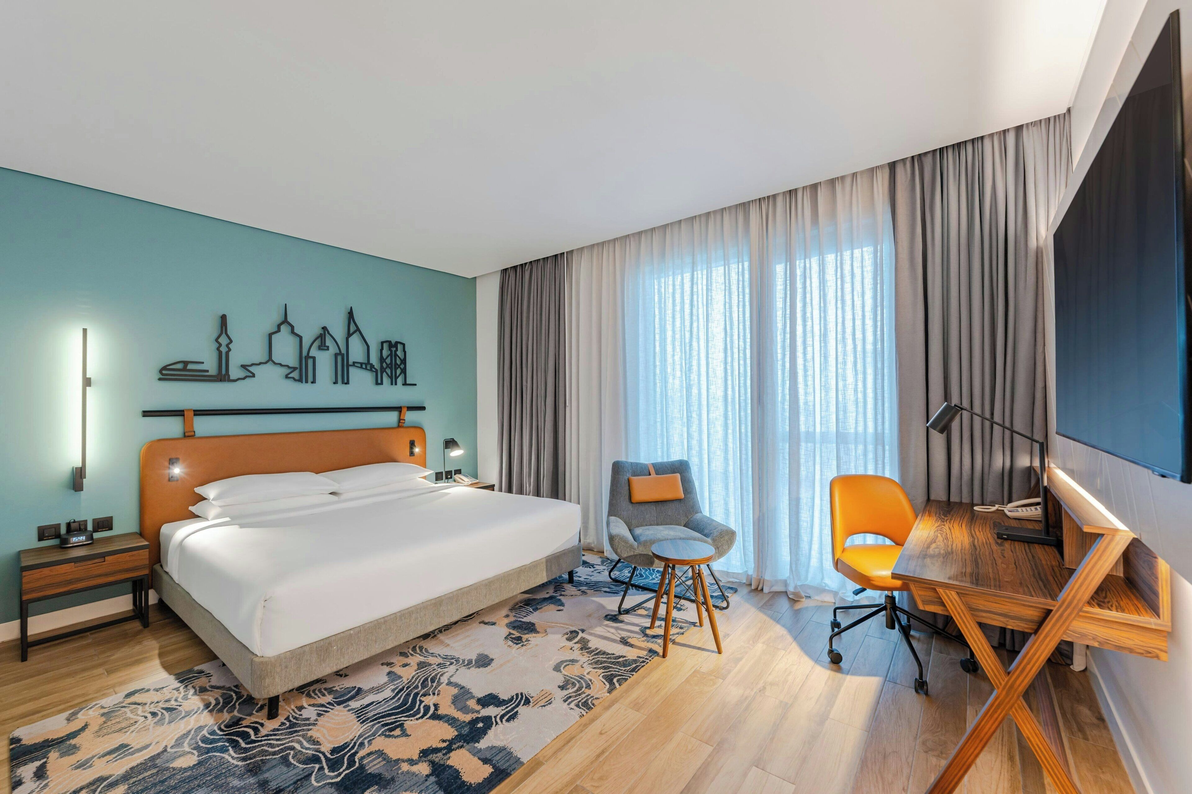 Una habitación de hotel moderna con una cama grande, un escritorio y una silla.