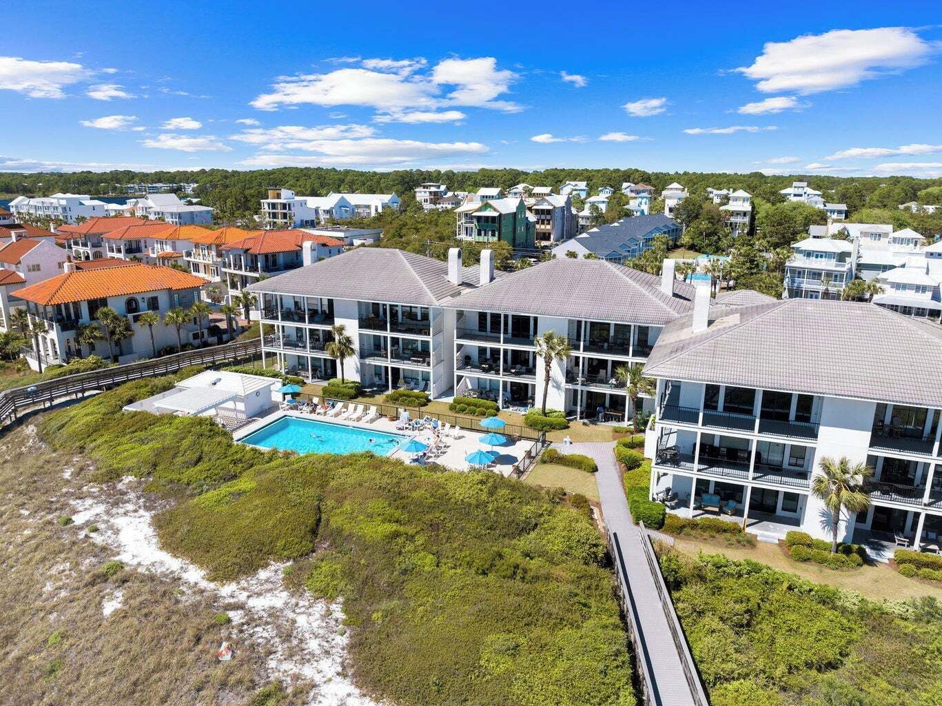 A coastal hotel with a large pool, multiple buildings, and a beach view.
