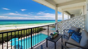 Un balcon avec vue sur la plage et l’océan, une piscine et du mobilier d’extérieur.