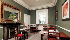 A dining room with a fireplace, a large mirror, and a window.