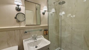 A bathroom with a sink, mirror, and shower.