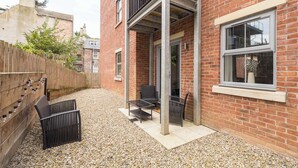 Un bâtiment en briques doté d’un patio aménagé avec du mobilier d’extérieur et un sol en gravier.