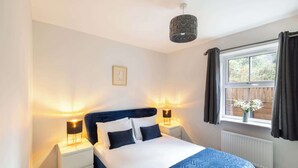 Une chambre à coucher avec un lit, deux lampes de chevet, une fenêtre avec des rideaux et un tableau au mur.