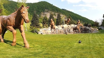 Une grande statue de cheval se dresse dans un espace verdoyant, avec une chaîne de montagnes en arrière-plan.