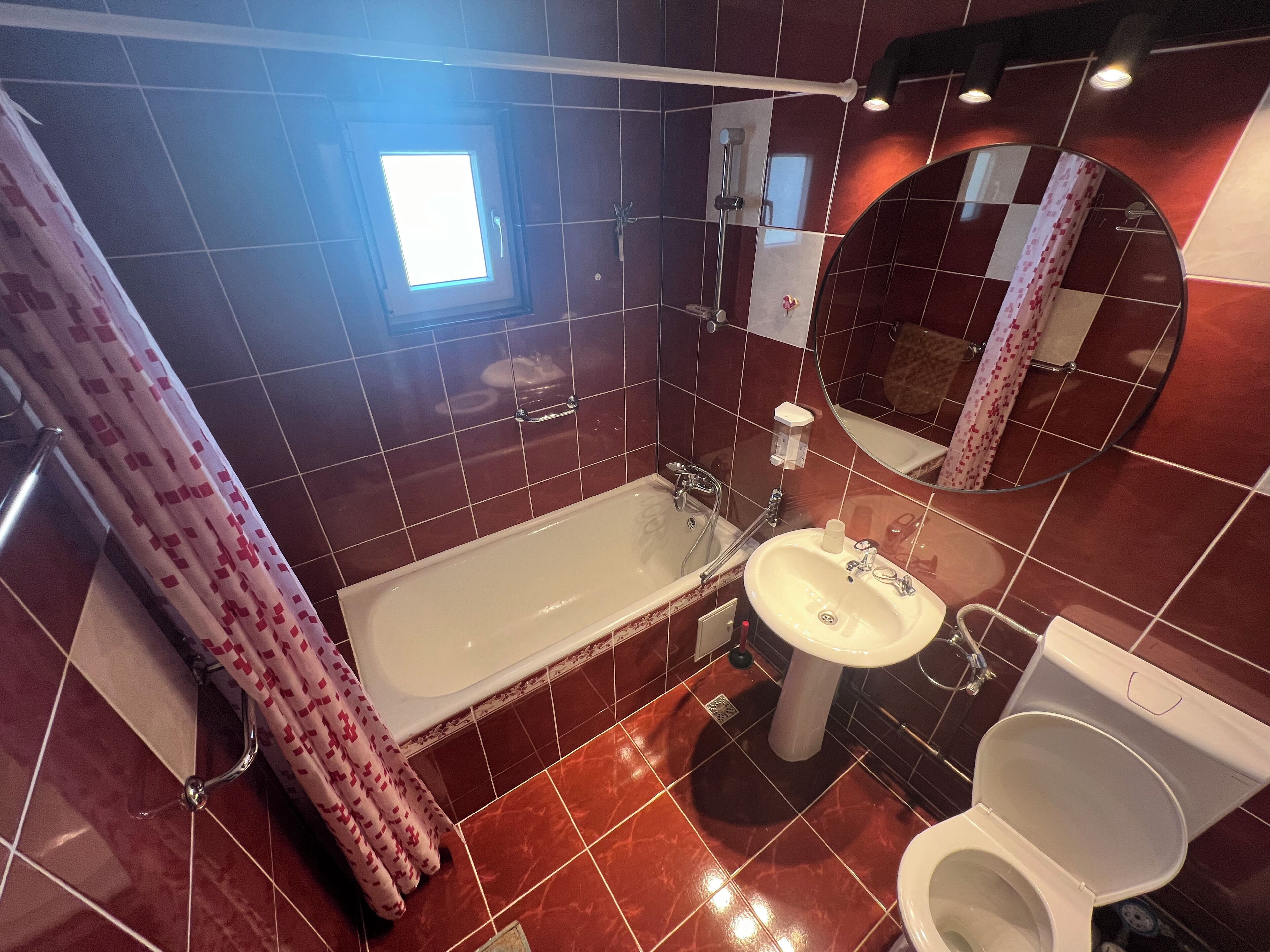 Et badeværelse med badekar, vask, toilet og et spejl.