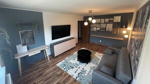 Una sala de estar moderna con un televisor de pantalla plana, un sofá, una mesa de centro y una alfombra estampada.