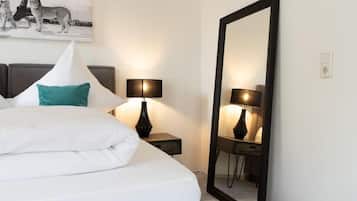 Ein Hotelzimmer mit einem Bett, zwei Nachttischlampen, einem großen Spiegel und einem Bild von Geparden an der Wand.