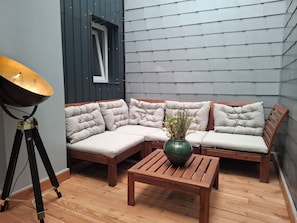 A corner seating area with a cushioned bench and a small table, a tripod lamp, and a vase with plants.