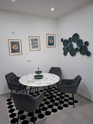 A modern dining area with a round table, four chairs, and a black and white patterned rug.
