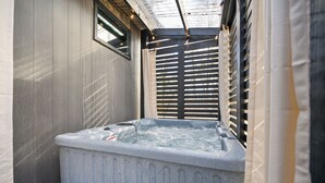 Un área de spa con un jacuzzi, paredes de madera y un ventanal con persianas.