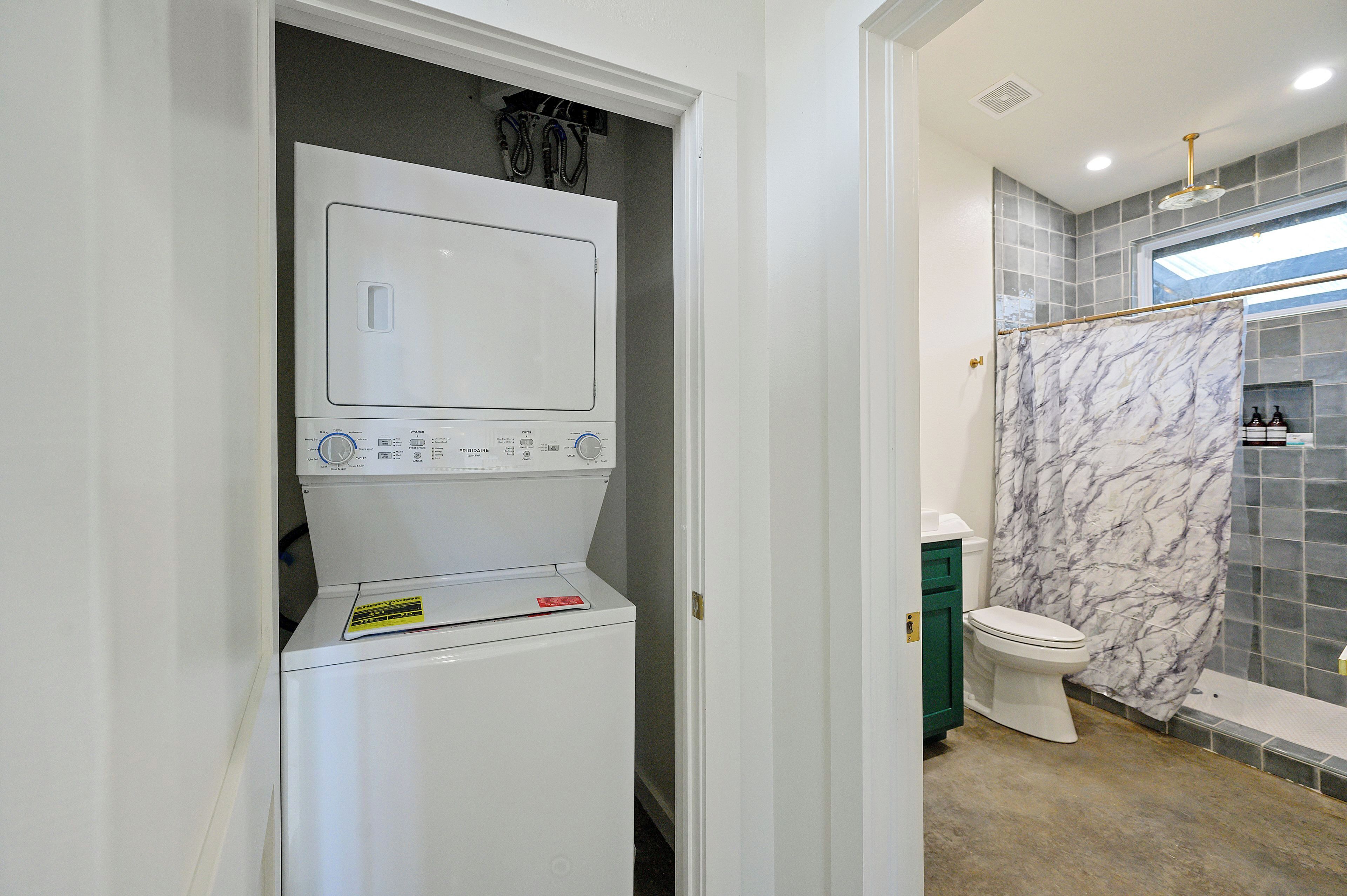 A compact bathroom with a white washing machine, a toilet, and a marble shower curtain.