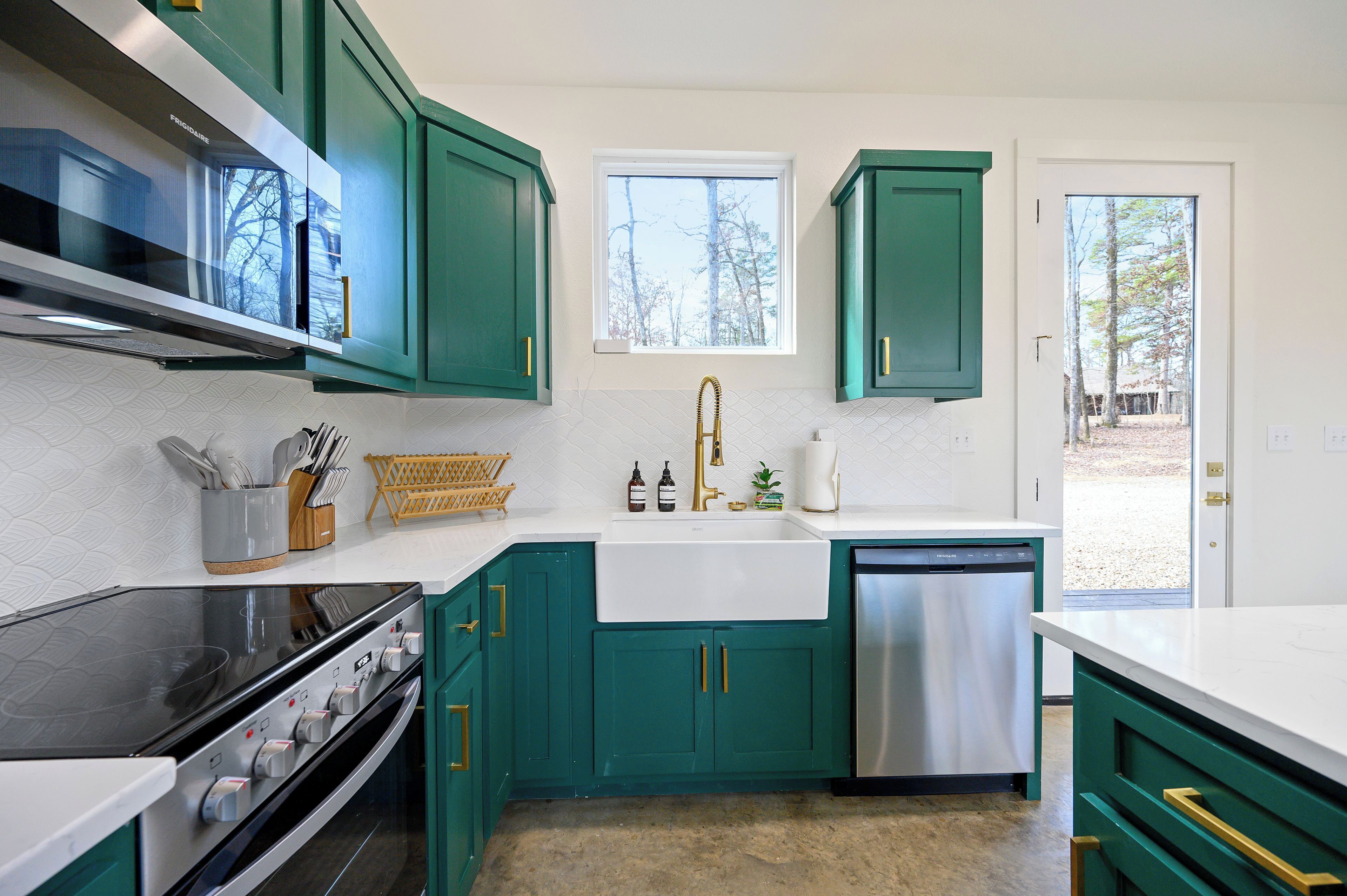 Een moderne keuken met blauwgroene kastjes, een roestvrijstalen vaatwasser en een zwart fornuis.