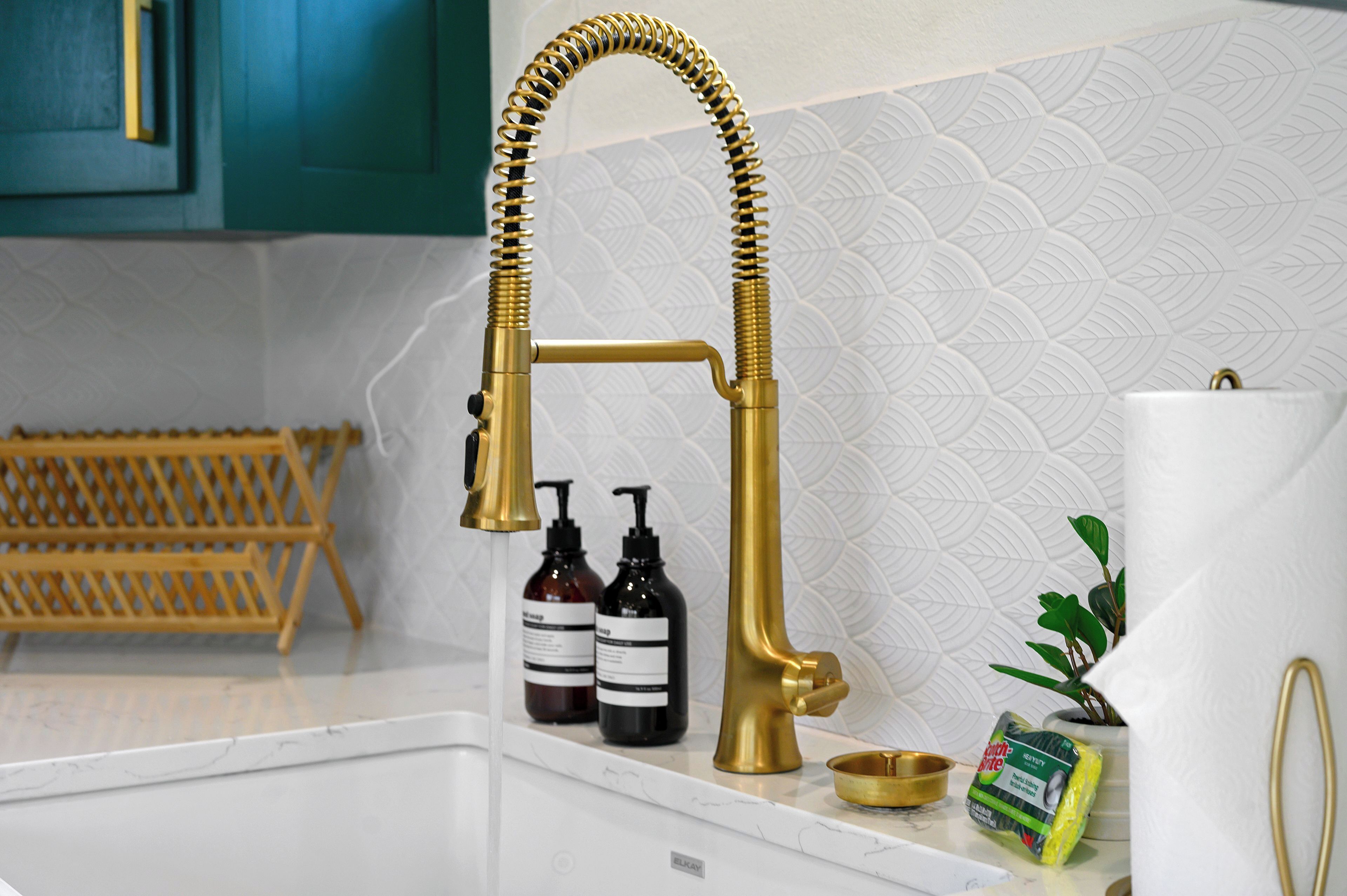 Een keuken met een gouden kraan, een houten rek en toiletartikelen.
