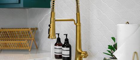 Een keuken met een gouden kraan, een houten rek en toiletartikelen.