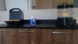 Egy konyhapult, rajta egy kávéfőző, egy doboz itambé joghurt és egy tálca kekszekkel.