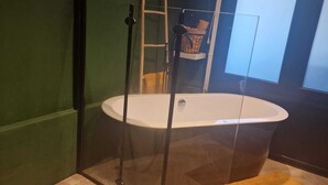 A bathroom with a freestanding bathtub, a glass shower enclosure, and a herringbone-patterned floor. - Tiny wellness room  in Nieuwegein near Utrecht (Nieuwegein)