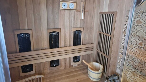A sauna room with wooden walls, a wooden bench, a bucket, and a heater. - Tiny wellness room  in Nieuwegein near Utrecht (Nieuwegein)