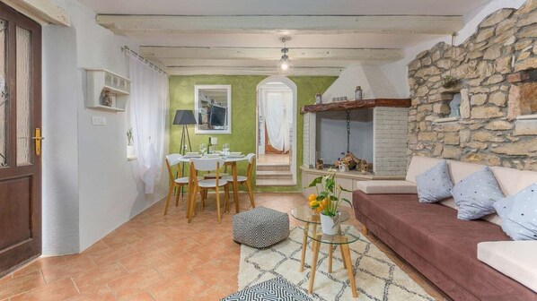 Una sala de estar acogedora con chimenea de piedra, un comedor con mesa y sillas, y un sofá con cojines.