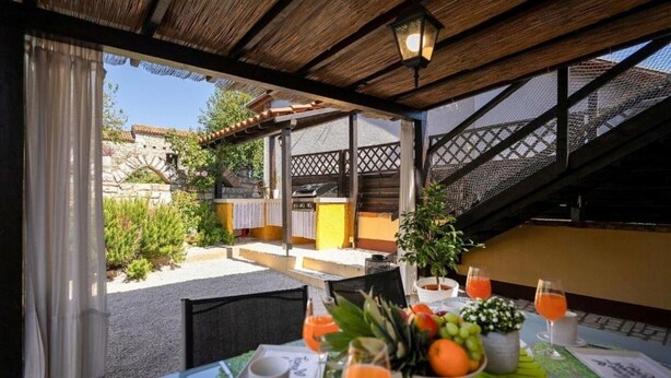 A covered outdoor dining area with a table set for two, featuring a view of a stone building and a staircase. - Rustic Casa Dvi Mendule with swimming pool (Nova Vas)