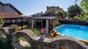 A backyard with a swimming pool, stone walls, and a covered patio area. - Rustic Casa Dvi Mendule with swimming pool (Nova Vas)