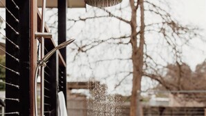 A showerhead with water spraying out, a towel hanging on a rack, and a wooden deck.