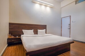 Una cama bien hecha con un cabecero de madera, una mesita de noche con una lámpara y una puerta con cerradura.