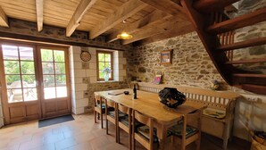 Un comedor rústico con una mesa y sillas de madera, paredes de piedra y un ventanal grande.