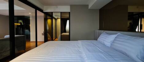 Ein modernes Hotelzimmer mit einem großen Bett, einer Sitzecke und einer Glaskabine.