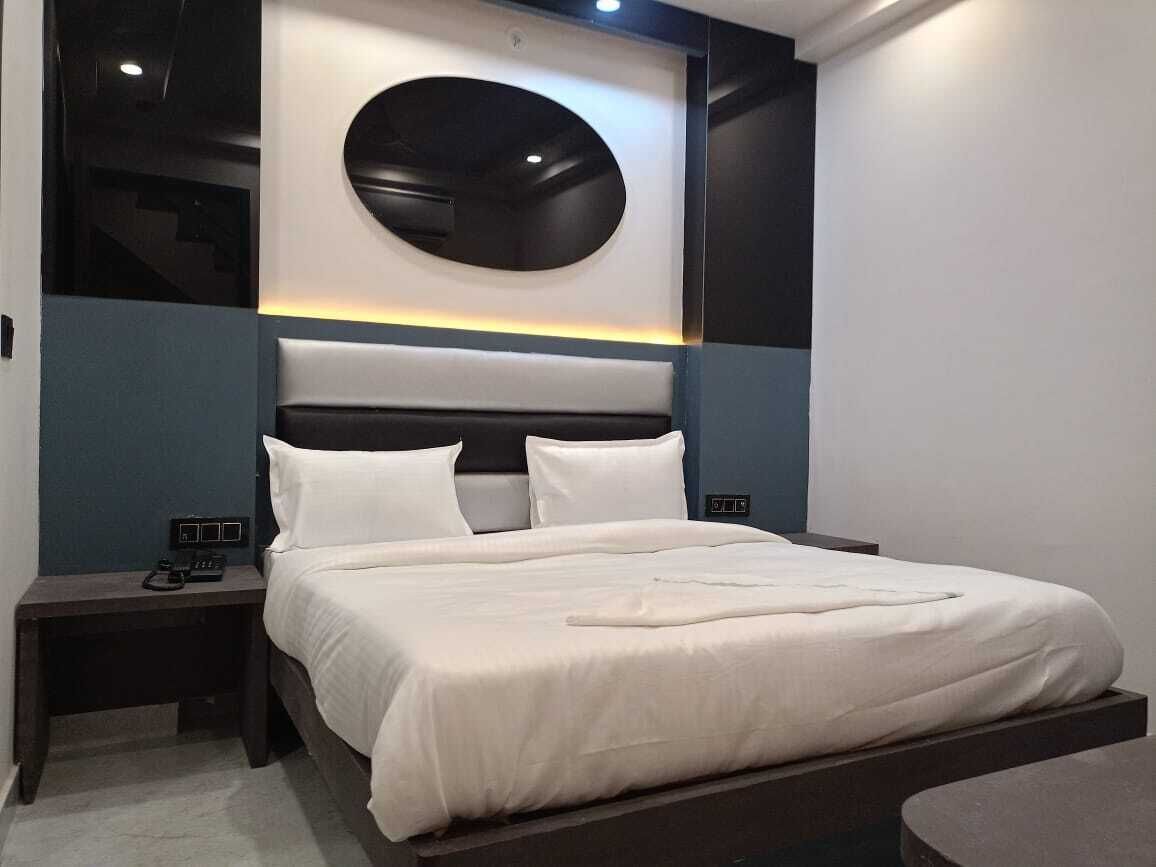 A modern bedroom with a large bed, a round wall-mounted light, and a built-in bench at the foot of the bed.