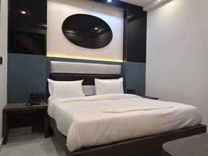 A modern bedroom with a large bed, a round wall-mounted light, and a built-in bench at the foot of the bed.