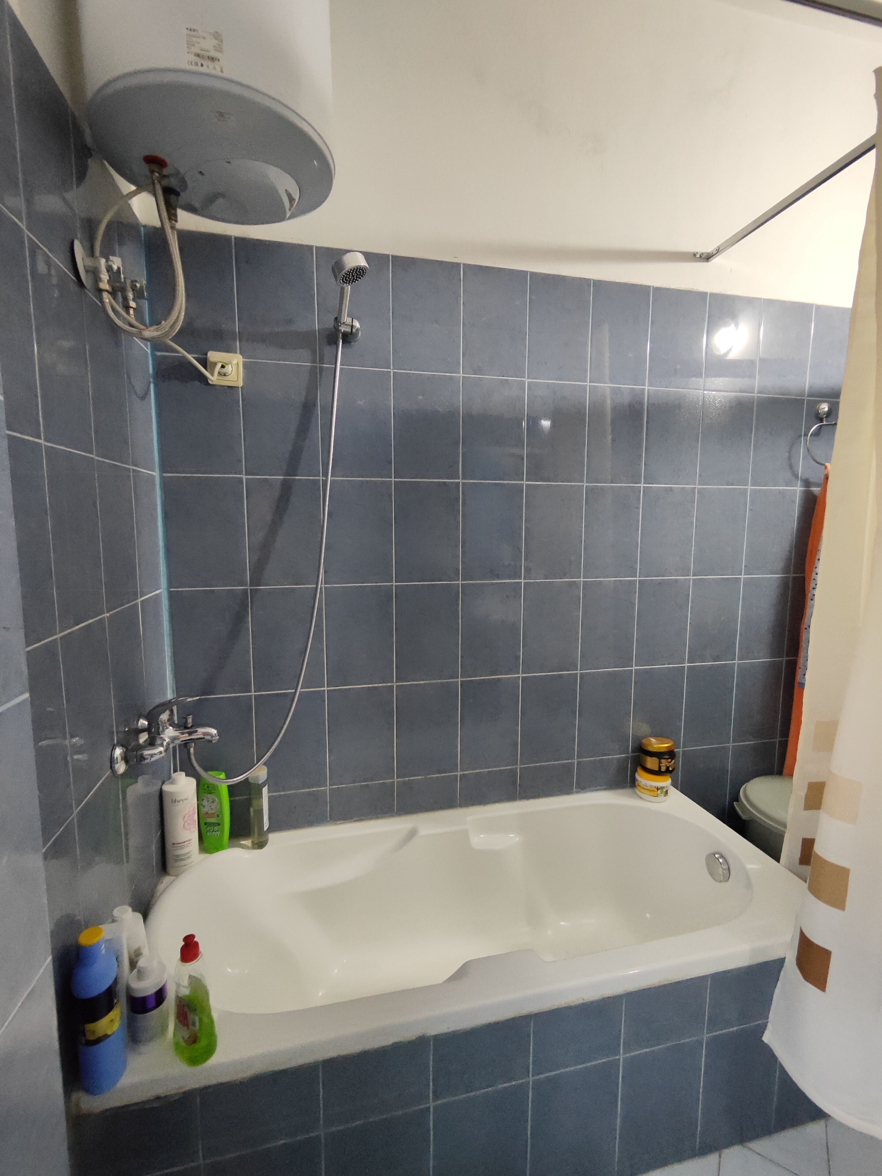 Et badeværelse med badekar, brusehoved og toilet.