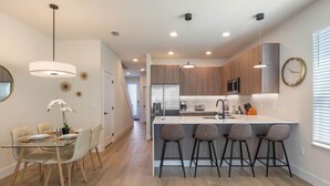 Una cocina moderna con una isla central, taburetes de bar e iluminación colgante.