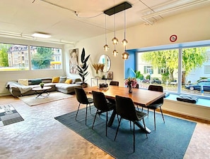 A modern living room with a dining area, large windows, and a view of the street. - Stylish 3-bedroom apartment, 120 m² (Zürich)