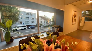 A room with a large window, a wooden table, and a vase of flowers. - 120m2 stylish 3-bedroom flat (Zürich)