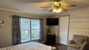 A bedroom with a bed, a chair, a television, and a door.