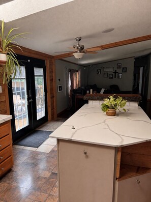 A kitchen with a marble countertop, wooden cabinets, a ceiling fan, and a potted plant.