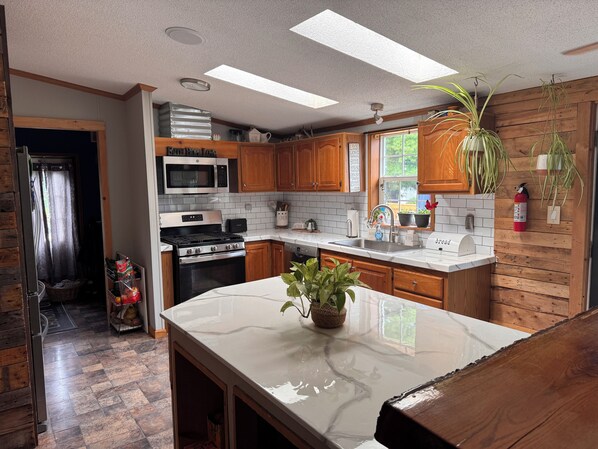 A kitchen with wooden cabinets, a stainless steel stove, a microwave, and a sink.